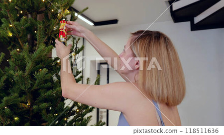 Young caucasian mother preparing for New Year and Christmas decorates home. Young adult woman immersed in getting ready for New Year and Christmas planning for joyful spirit and celebration. 118511636