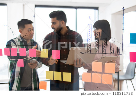 Business team brainstorming ideas with sticky notes and charts Business team brainstorming ideas with sticky notes and charts 118511758
