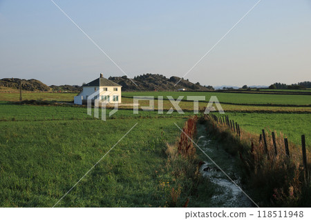 White house surrounded by green meadows and fields, Rogaland, Norway. 118511948