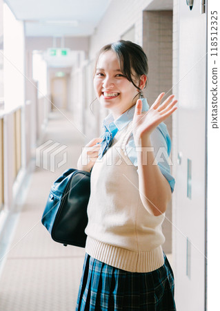 一名身穿制服的高中女生在入口處向家人揮手致意 118512325