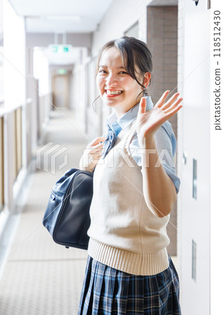 A high school girl in uniform waving to her family at the entrance 118512430