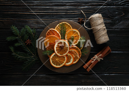 Dried orange slices on wooden plate, Christmas tree branches and twine on wooden background, top view 118513360