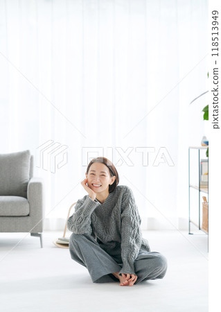 Middle-aged woman sitting in the living room and smiling Middle-aged woman sitting in the living room and smiling 118513949