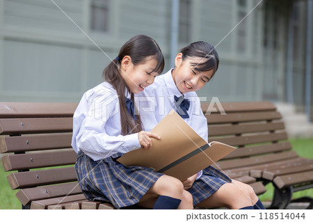 A student sitting on a bench and looking at his notebook A student sitting on a bench and looking at his notebook 118514044