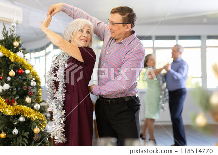 Happy elderly woman and middle-aged male partner successfully perform mesmerizing movements of paso doble dance during celebration Christmas 118514770