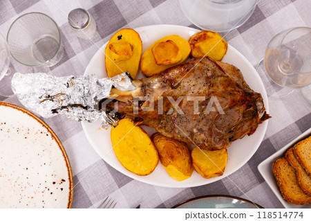 Traditional Spanish lunch is served - fried baked leg of lamb with side dish of potatoes 118514774
