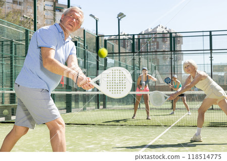 Determined sporty older man doing his best playing padel in court 118514775
