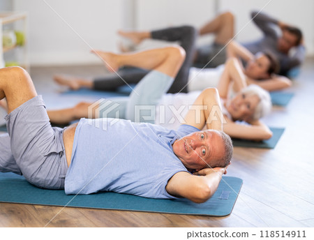 Pensioners doing fitness in group classes - doing exercises for abdominal muscles Pensioners doing fitness in group classes - doing exercises for abdominal muscles 118514911