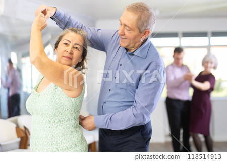 Happy mature woman enjoying impassioned merengue with male partner in dance class. Social dancing concept 118514913
