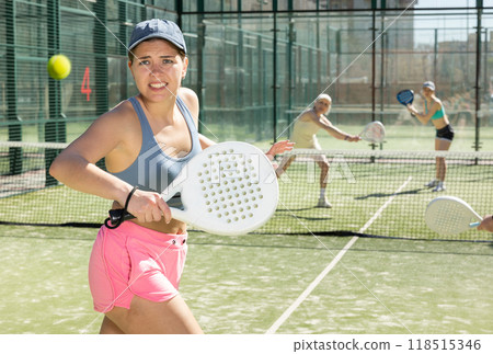 Young woman looking back after the ball while playing Padel Tennis in tennis court 118515346