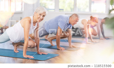 Diligent women and men doing body stretching before yoga class in a fitness studio Diligent women and men doing body stretching before yoga class in a fitness studio 118515500