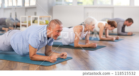 Pensioners in sportswear performing plank exercise during group Pilates workout in fitness studio 118515532