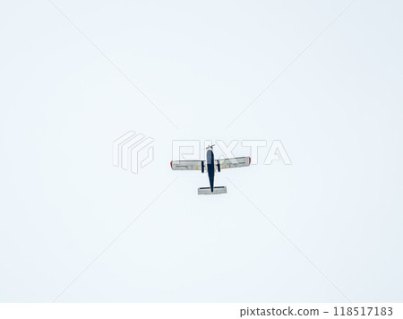 Small ultralight airplane with overhead wing and single propeller flying in sunset sky. 118517183