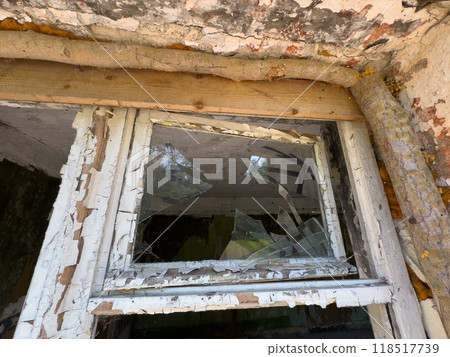 Broken window of an abandoned building with peeling paint 118517739