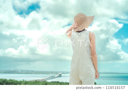 從宮古島的壯觀景點看到伊良部大橋和戴草帽的女人 從宮古島的壯觀景點看到伊良部大橋和戴草帽的女人 118518157