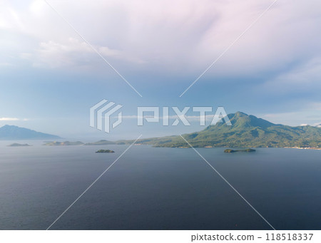 Aerial view of the ocean surface with mountains and clouds in the background 118518337
