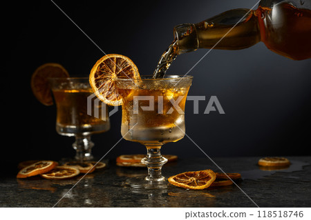 Rum is poured from a bottle into a glass with ice. Rum is poured from a bottle into a glass with ice. 118518746