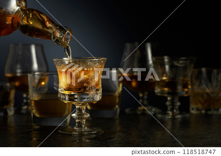 Whiskey is poured from a bottle into a glass. 118518747