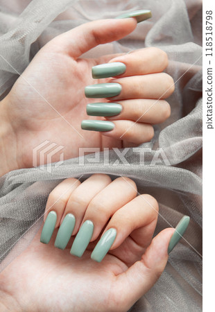 Elegant green manicure displayed on softly draped fabric with hands positioned artistically 118518798