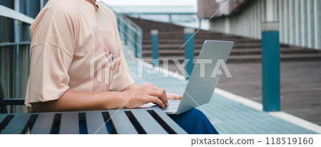 Confident female entrepreneur sits on a metal table next to the corridor in a modern city, She working with laptop computer and online marketing service, Working on laptop connected to public wi-fi. Confident female entrepreneur sits on a metal table next to the corridor in a modern city, She working with laptop computer and online marketing service, Working on laptop connected to public wi-fi. 118519160