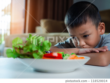 Little cute boy refuses to eat healthy vegetables, Children do not like to eat vegetables, Nutrition healthy eating habits for kids concept, Children do not like to eat vegetables. Little cute boy refuses to eat healthy vegetables, Children do not like to eat vegetables, Nutrition healthy eating habits for kids concept, Children do not like to eat vegetables. 118520014