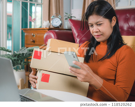 Asia women working business SME online at home her checking order from smartphone for customer and online delivery for ready packing, Checking orders from customers with digital laptop. Asia women working business SME online at home her checking order from smartphone for customer and online delivery for ready packing, Checking orders from customers with digital laptop. 118520262