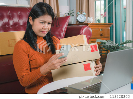 Asia women working business SME online at home her checking order from smartphone  for customer and online delivery for ready packing, Checking orders from customers with digital laptop. 118520263
