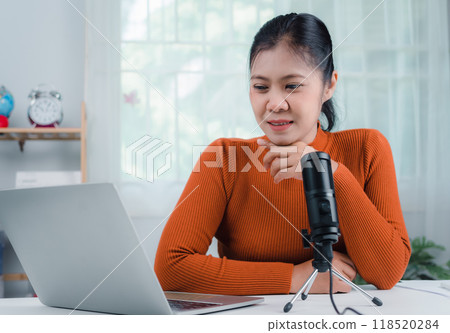 Content creator concept, woman talking into microphone on stand, lead on-line communication, discuss topic, looks at notebook screen, Engaged in streaming, Virtual meeting event, Podcast, Webinar. Content creator concept, woman talking into microphone on stand, lead on-line communication, discuss topic, looks at notebook screen, Engaged in streaming, Virtual meeting event, Podcast, Webinar. 118520284