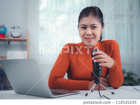 Content creator concept, woman talking into microphone on stand, lead on-line communication, discuss topic, looks at notebook screen, Engaged in streaming, Virtual meeting event, Podcast, Webinar. 118520285