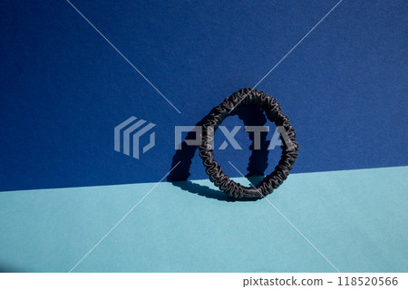 a dark blue silk hair scrunchie for women sitting on top of a blue and cyan surface, minimalism, 118520566