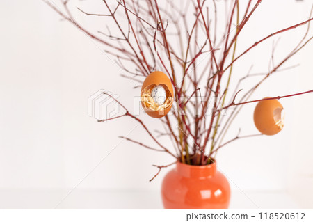 Easter home decor craft concept, a vase filled with branches with easet craft eggs hanging on it Easter home decor craft concept, a vase filled with branches with easet craft eggs hanging on it 118520612