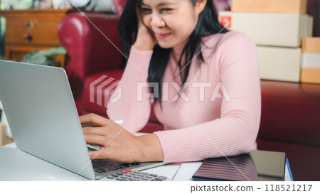 Businesswomen working business SME online at home her checking order from laptop for customer and online delivery for ready packing, Checking orders from customers with digital laptop, Small business. 118521217
