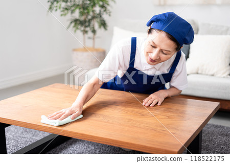 Senior female housekeeper in a white polo shirt with a blue apron 118522175