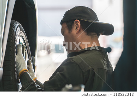 A male mechanic removing and installing tires on a lifted car A male mechanic removing and installing tires on a lifted car 118522318