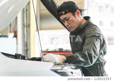 Male auto mechanic opening the hood of a car Male auto mechanic opening the hood of a car 118522357