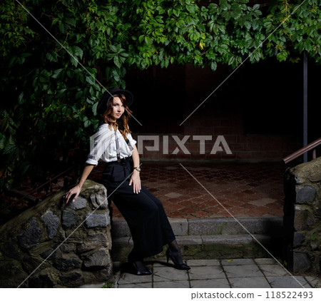 Woman in retro-styled outfit poses on stone steps surrounded by greenery 118522493