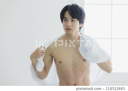 A naked young man wiping his body with a bath towel 118522683
