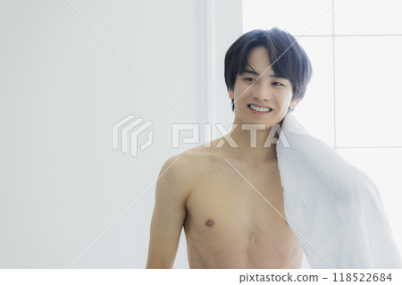 A naked young man wiping his body with a bath towel 118522684