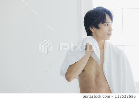A naked young man wiping his body with a bath towel A naked young man wiping his body with a bath towel 118522686