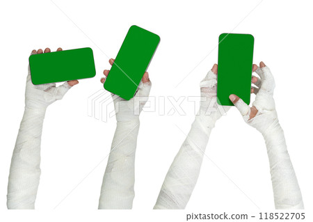 Set of mummy hands have bandages on them holding mobile phones or cellphones with green screens 118522705