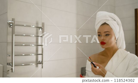 Woman applying red lipstick in bathroom mirror. Woman applying red lipstick in bathroom mirror. 118524302