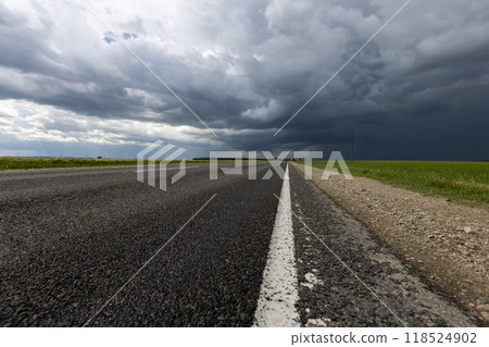 narrow rural paved road before a thunderstorm narrow rural paved road before a thunderstorm 118524902