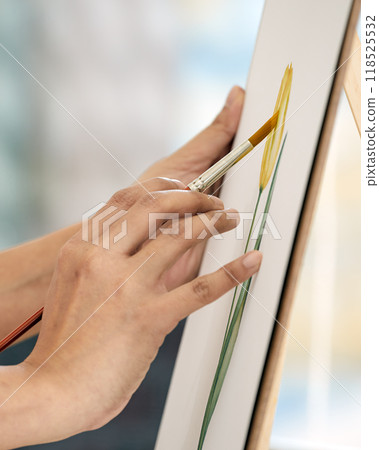 close-up of hands painting yellow flower on canvas with brush. focuses on precision and creativity of artistic process 118525532
