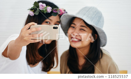 Two women taking selfie, one wearing floral headband andother gray hat, both smiling Two women taking selfie, one wearing floral headband andother gray hat, both smiling 118525537