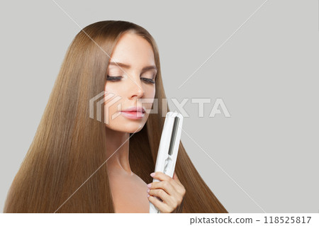 Elegant woman with long hair using a straight hair iron Elegant woman with long hair using a straight hair iron 118525817