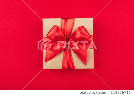 Cardboard gift box with bow on red background. Flat lay. Top view. 118526711