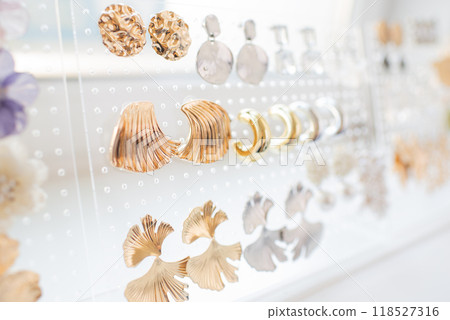 Elegant display of various gold and silver earrings on a transparent holder with a soft-focus background. 118527316