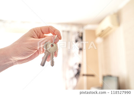 Hand holding keys in bright room signifying real estate success, home ownership 118527990