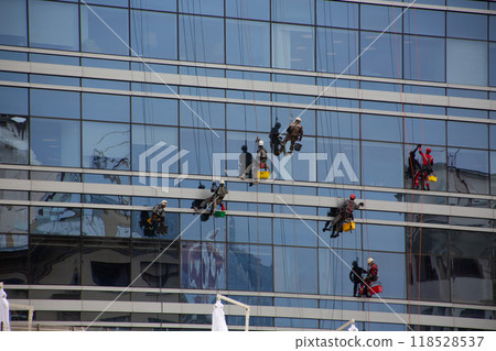 Industrial climbers are cleaning building, workers are cleaning glass windows of multi story building at high altitude 118528537