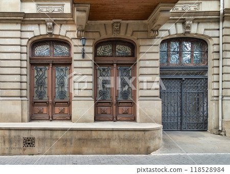 Architectural elegance with intricate wooden doors and wrought iron gate in a historic urban setting Architectural elegance with intricate wooden doors and wrought iron gate in a historic urban setting 118528984